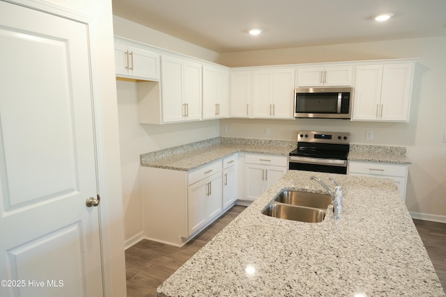 kitchen with dark hardwood / wood-style floors, sink, white cabinets, stainless steel appliances, and light stone countertops