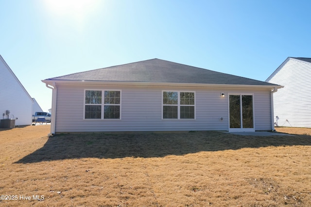 rear view of property with central AC and a yard