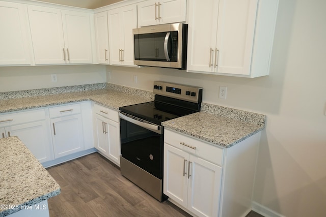 kitchen featuring hardwood / wood-style floors, stainless steel appliances, white cabinets, and light stone countertops