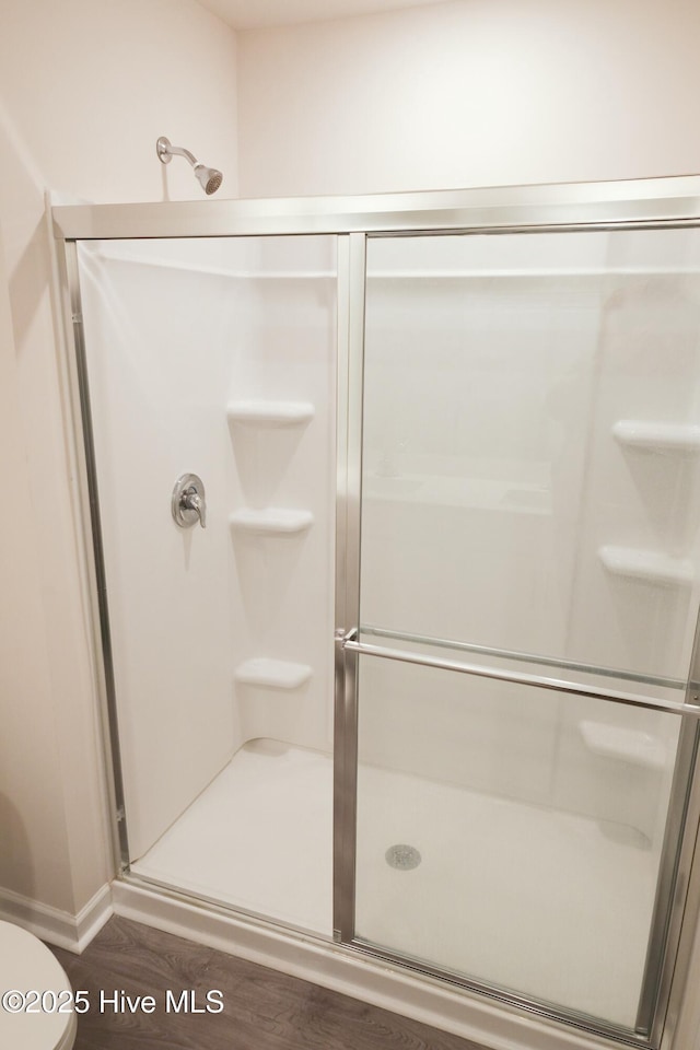 bathroom with toilet, an enclosed shower, and hardwood / wood-style floors