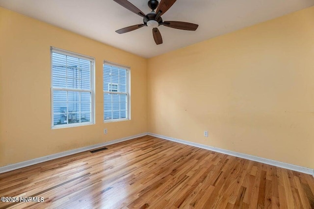 spare room with ceiling fan, plenty of natural light, and light wood-type flooring