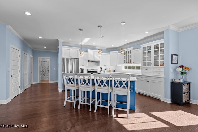 kitchen with a kitchen bar, decorative light fixtures, a center island with sink, stainless steel appliances, and white cabinets