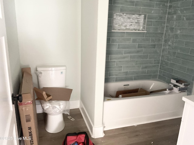 bathroom featuring vanity, a tub to relax in, hardwood / wood-style flooring, and toilet