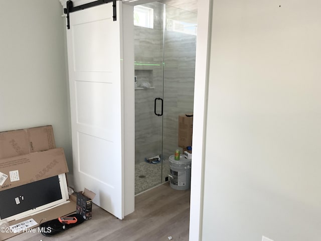 bathroom with hardwood / wood-style flooring and a shower with shower door