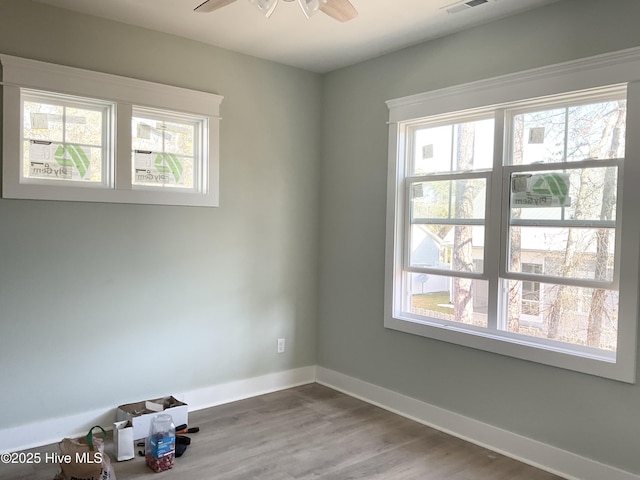 unfurnished room featuring wood-type flooring, a wealth of natural light, and ceiling fan