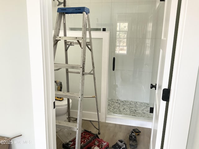 bathroom featuring hardwood / wood-style flooring, toilet, and a shower with shower door