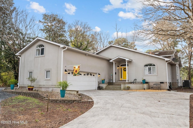 view of front of property with concrete driveway, central AC unit, a garage, and stucco siding