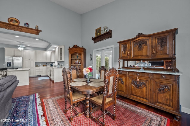 dining space featuring ceiling fan, dark hardwood / wood-style flooring, and a towering ceiling