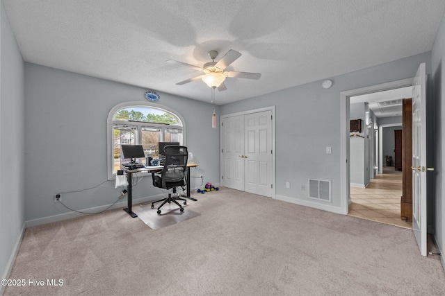 carpeted office featuring ceiling fan and a textured ceiling