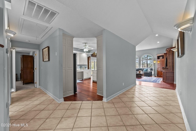 hall with light tile patterned flooring and lofted ceiling