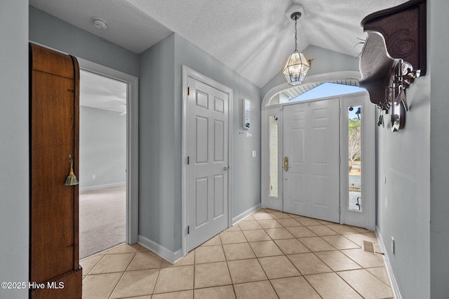 tiled entrance foyer featuring vaulted ceiling, a notable chandelier, and a textured ceiling