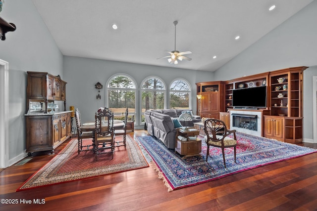 living room featuring dark wood-type flooring, ceiling fan, and high vaulted ceiling