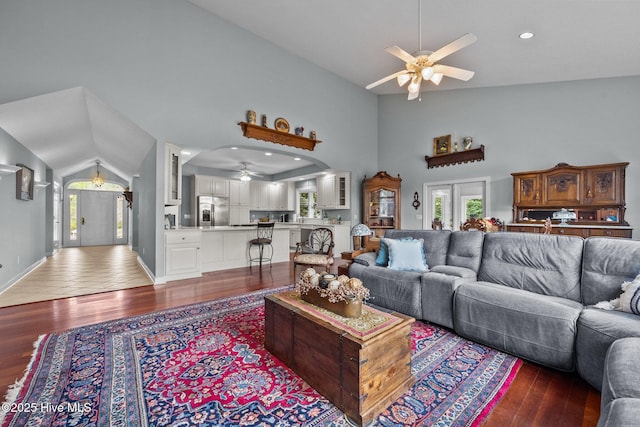 living room with dark wood-type flooring, ceiling fan, and high vaulted ceiling