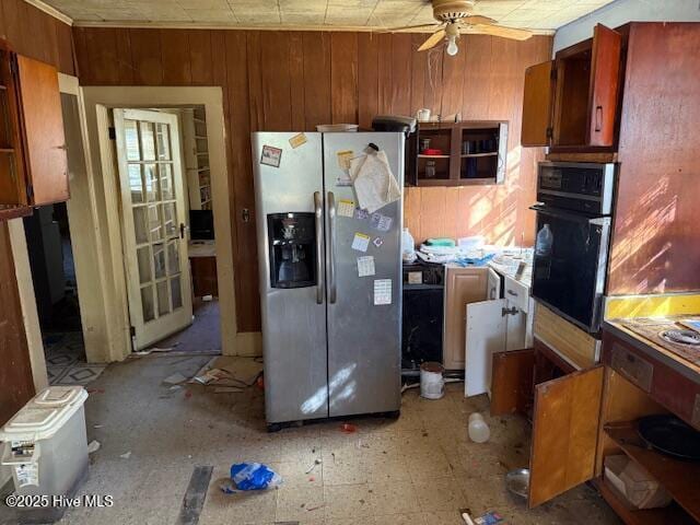 kitchen featuring ceiling fan, wooden walls, oven, and stainless steel fridge with ice dispenser