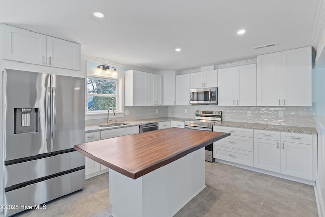 kitchen with appliances with stainless steel finishes, sink, and white cabinets