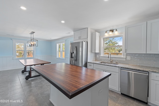 kitchen featuring sink, white cabinetry, hanging light fixtures, stainless steel appliances, and a kitchen island