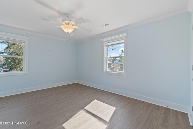 unfurnished room featuring ceiling fan, hardwood / wood-style flooring, ornamental molding, and a healthy amount of sunlight