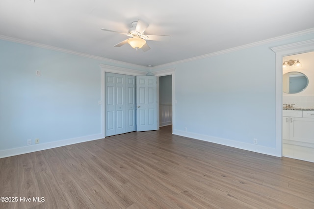 unfurnished bedroom featuring sink, light hardwood / wood-style flooring, ornamental molding, and a closet