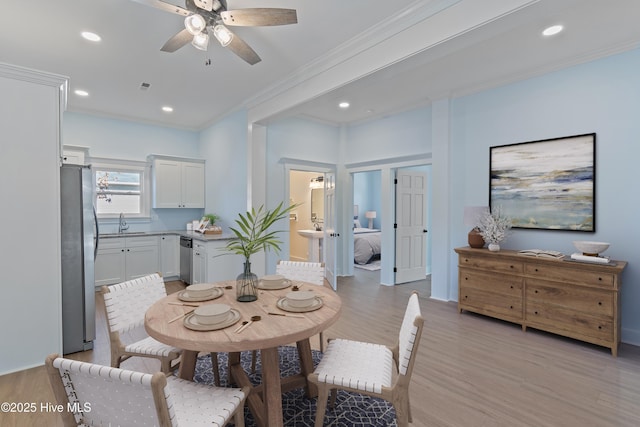 dining room featuring crown molding, sink, ceiling fan, and light hardwood / wood-style flooring