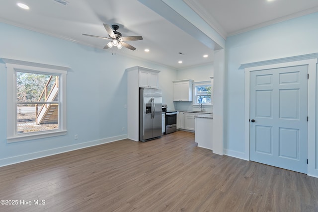 kitchen featuring white cabinetry, appliances with stainless steel finishes, ornamental molding, and light wood-type flooring