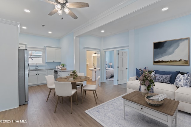 dining space with ornamental molding, sink, ceiling fan, and light hardwood / wood-style floors