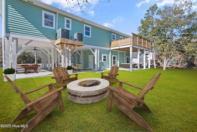 back of house with central air condition unit, a lawn, ceiling fan, a fire pit, and a patio