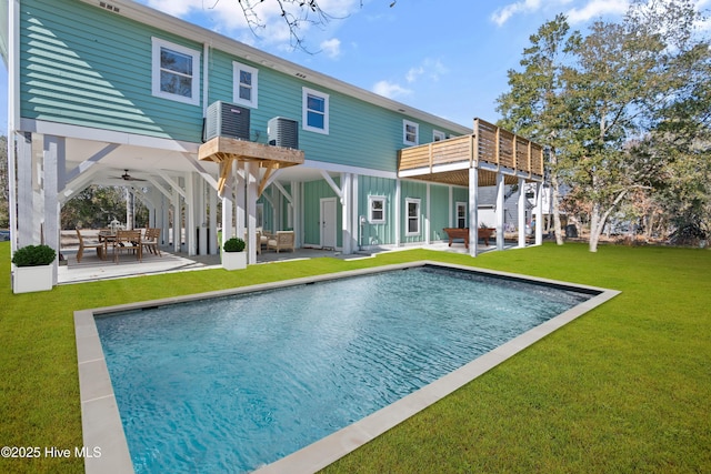 rear view of property with ceiling fan, a yard, a balcony, and a patio