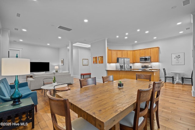 dining space featuring crown molding and light hardwood / wood-style floors