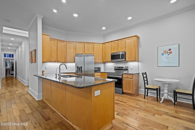 kitchen featuring sink, crown molding, dark stone countertops, appliances with stainless steel finishes, and kitchen peninsula