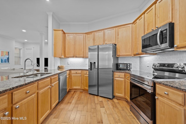 kitchen with dark stone countertops, sink, ornamental molding, and stainless steel appliances