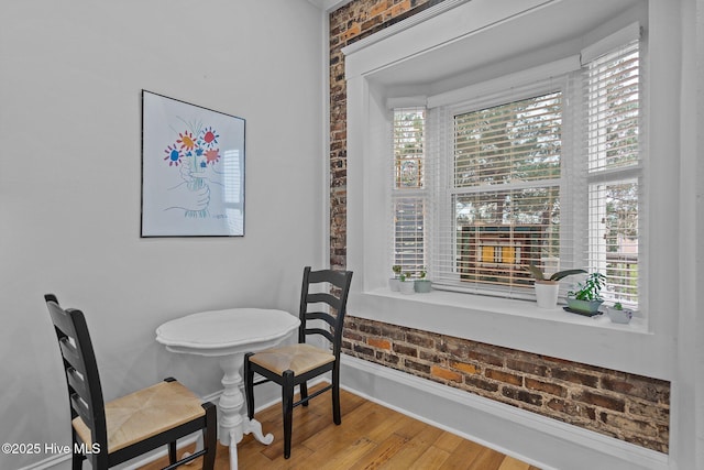 dining room with hardwood / wood-style flooring and brick wall