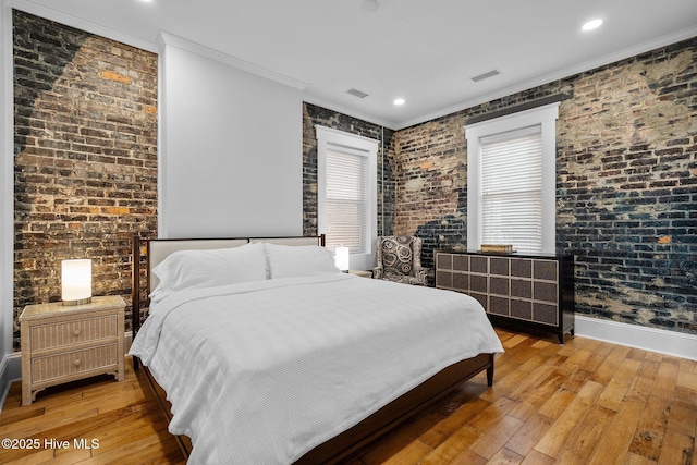 bedroom with crown molding, brick wall, and light hardwood / wood-style floors