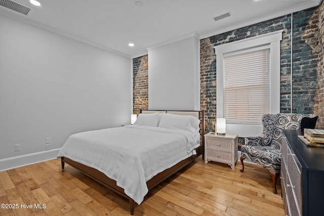 bedroom with ornamental molding, brick wall, and light hardwood / wood-style flooring