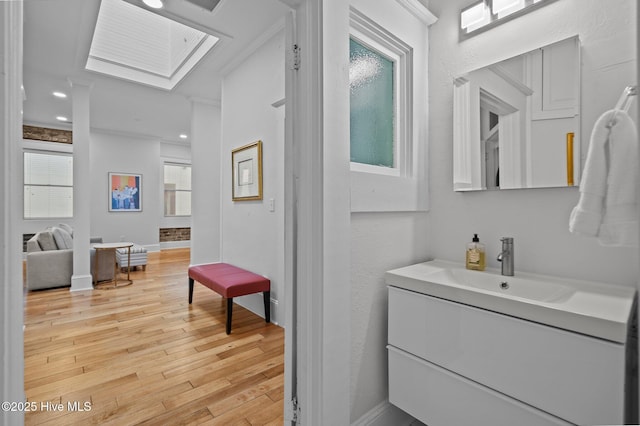 bathroom featuring ornamental molding, wood-type flooring, vanity, and a skylight