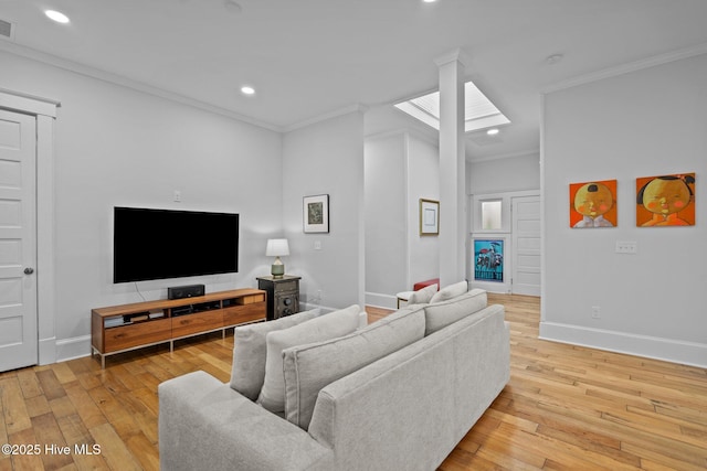 living room featuring ornamental molding, a skylight, and light wood-type flooring