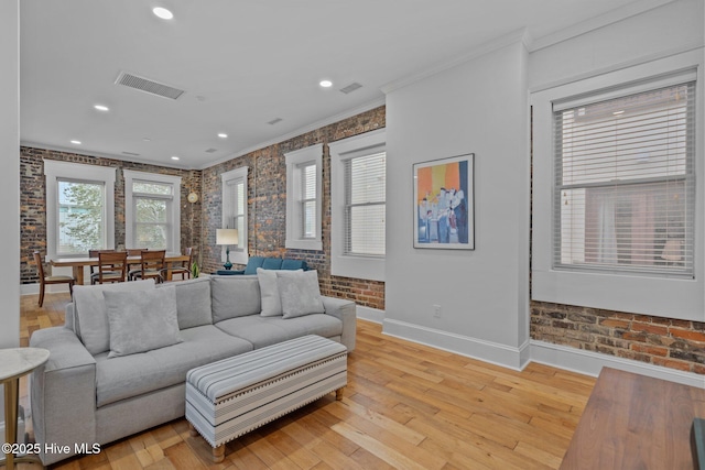 living room featuring crown molding, brick wall, and light hardwood / wood-style floors