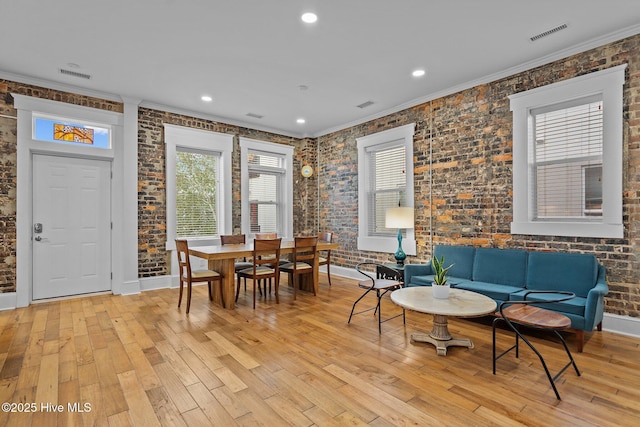 interior space with ornamental molding, brick wall, and light wood-type flooring