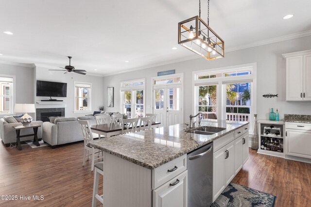 kitchen with sink, white cabinets, dishwasher, and a center island with sink