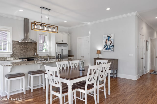 dining area with dark wood-type flooring, ornamental molding, and sink