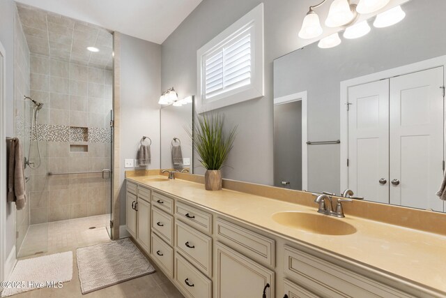 bathroom featuring a tile shower, vanity, tile patterned flooring, and a chandelier