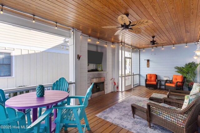 deck featuring ceiling fan and an outdoor living space with a fireplace