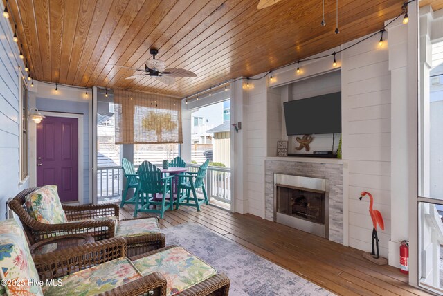 living room with an outdoor fireplace, hardwood / wood-style floors, rail lighting, ceiling fan, and wood ceiling