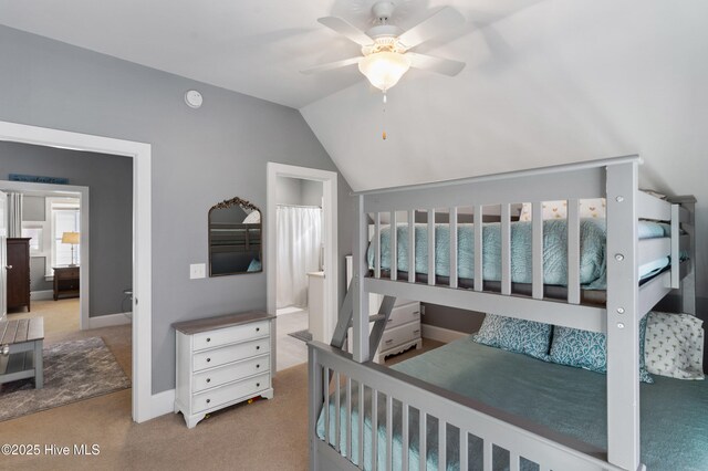 bedroom with vaulted ceiling, ensuite bathroom, ceiling fan, and carpet flooring