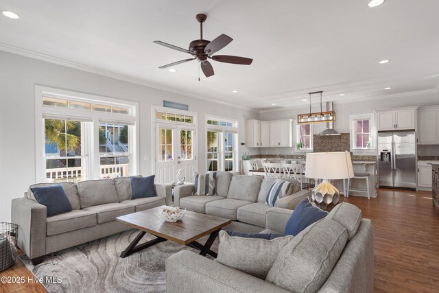 living room with dark wood-type flooring, plenty of natural light, ornamental molding, and ceiling fan