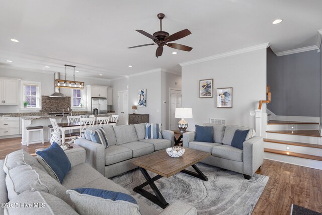 living room featuring ceiling fan, ornamental molding, and light hardwood / wood-style flooring