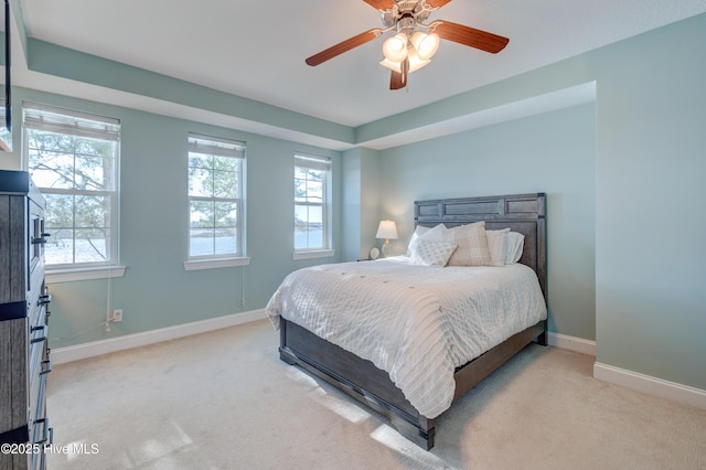 bedroom featuring light carpet, ceiling fan, multiple windows, and baseboards