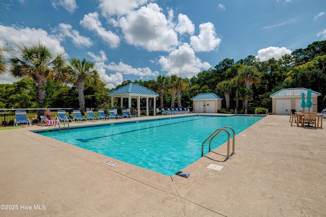 community pool with a patio, a gazebo, fence, a shed, and an outdoor structure