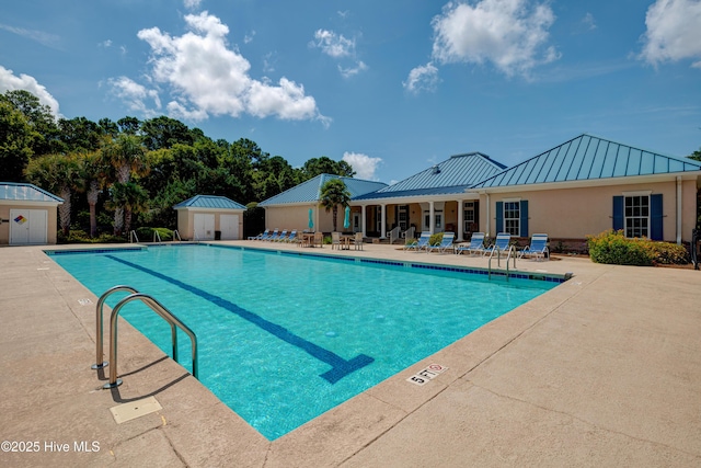 community pool featuring a shed, an outbuilding, and a patio