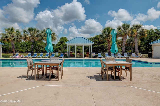 community pool with a patio area, fence, and a gazebo