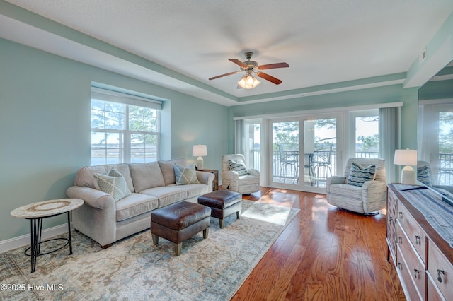 living room featuring a wealth of natural light, ceiling fan, baseboards, and wood finished floors